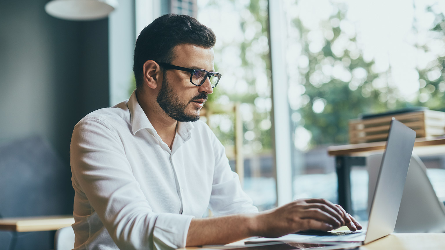 Young man wearing white shirt and eye glasses working with laptop