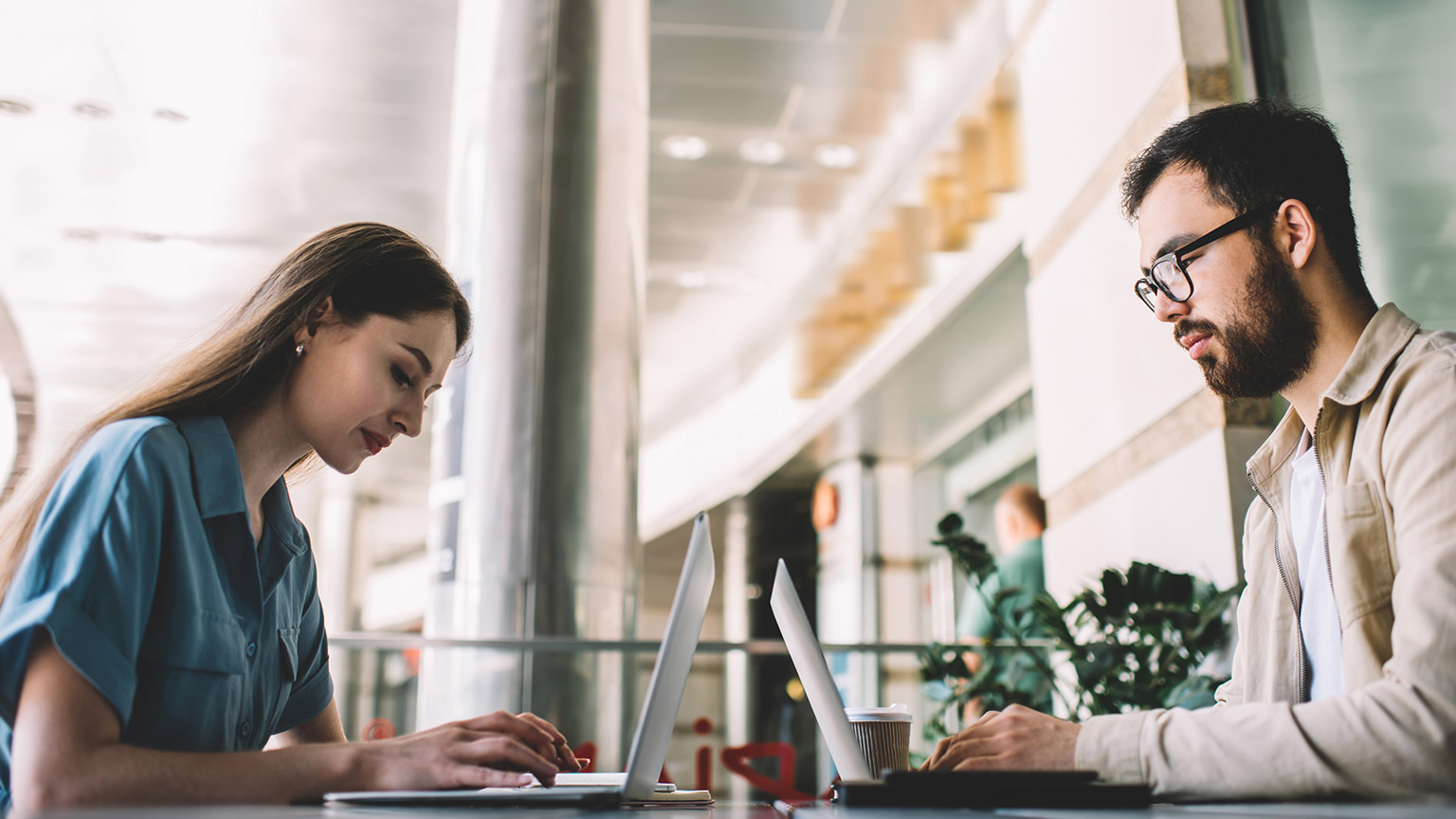 Two people working on laptops in an office