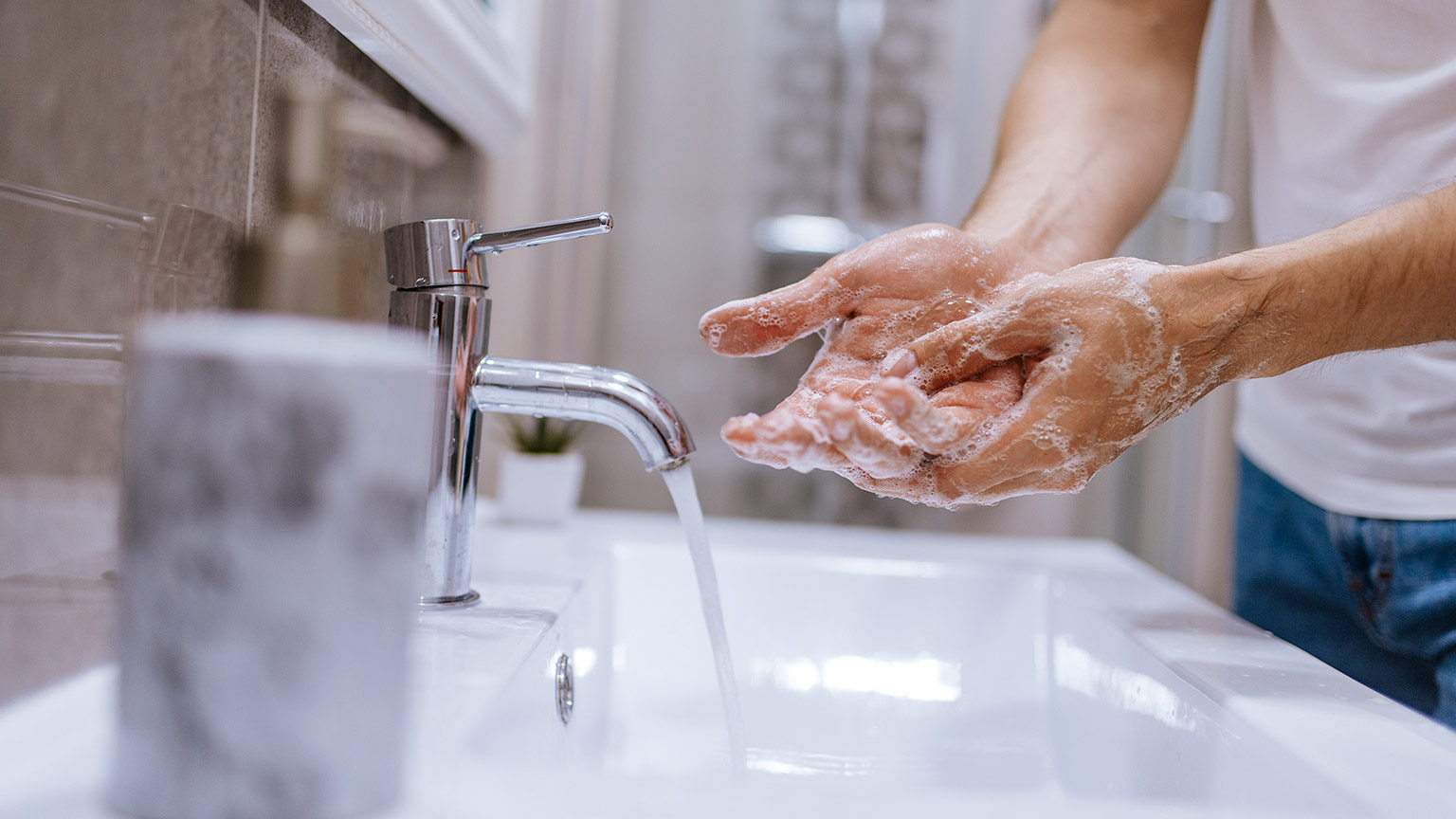 man washes his hands in the bathroom sink