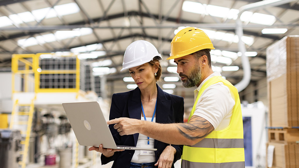 Female manager talking with foreman, checking production plan on notebook