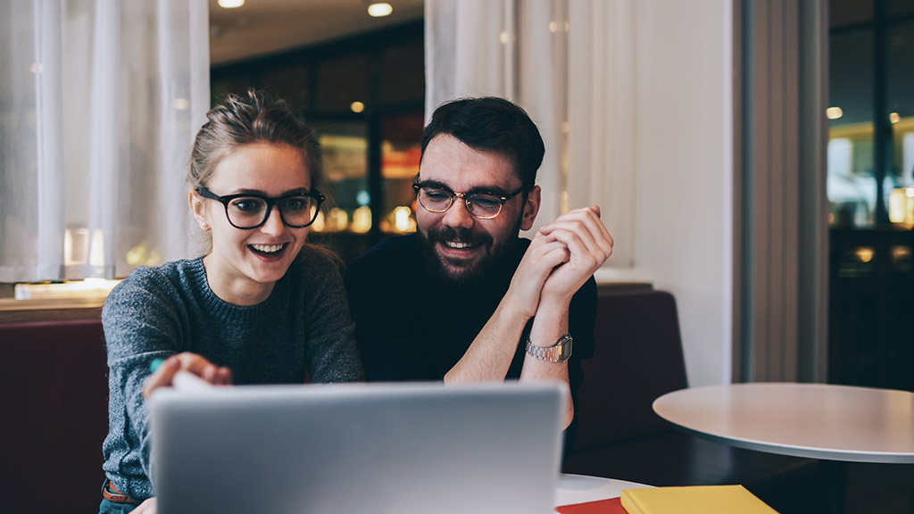 Cheerful good looking employees in cool spectacles watching funny webinar in webpage on laptop