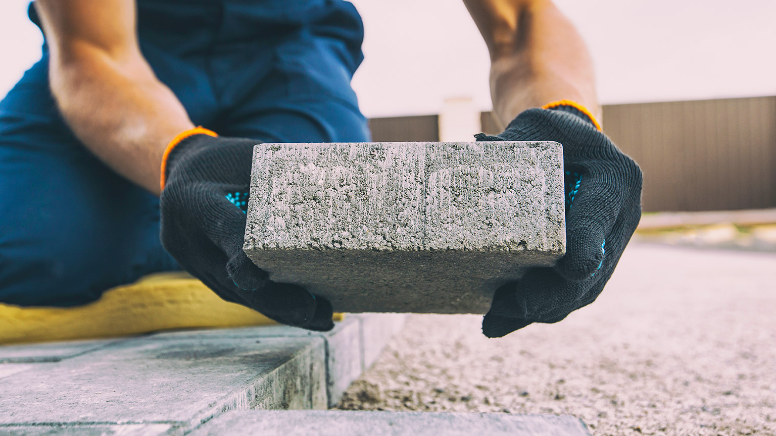 A close view of a person laying pavers in a backyard