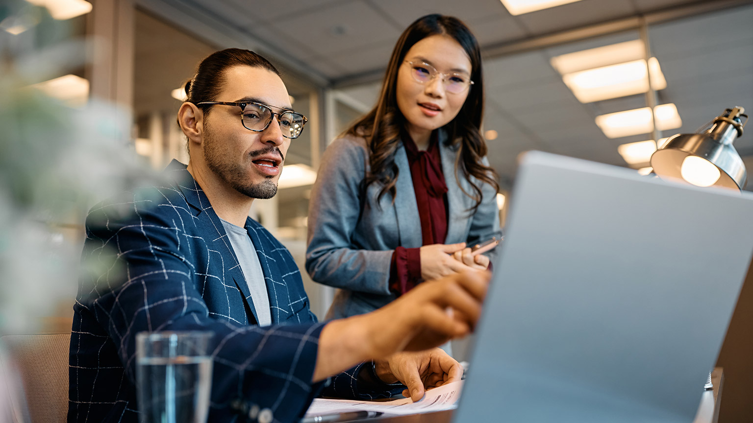 Two coworkers discussing a project in an office