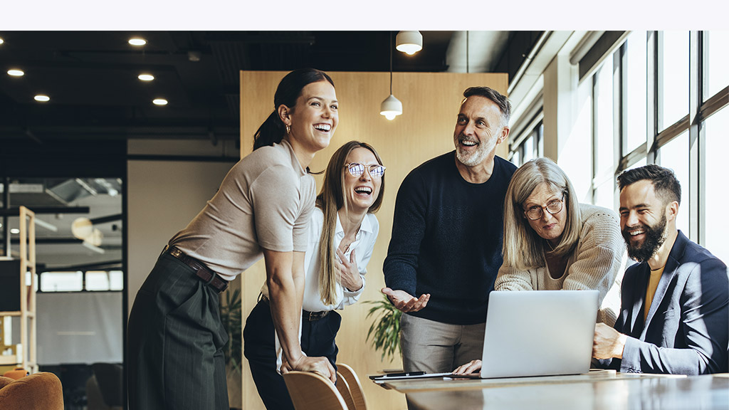 Happy businesspeople laughing while collaborating on a new project in an office