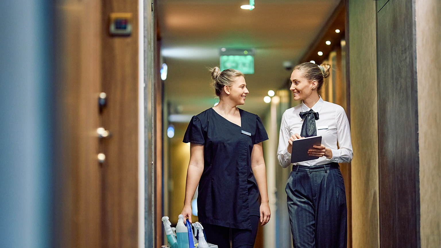 Happy housekeeping executive using touchpad while communicating 