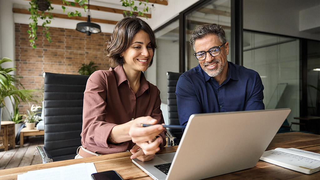 Business team of two executives working together using laptop in office