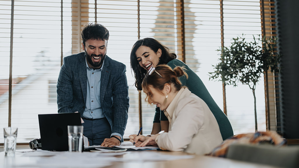 Three business associates are collaborating and reviewing statistics and paperwork, reflecting a successful work environment