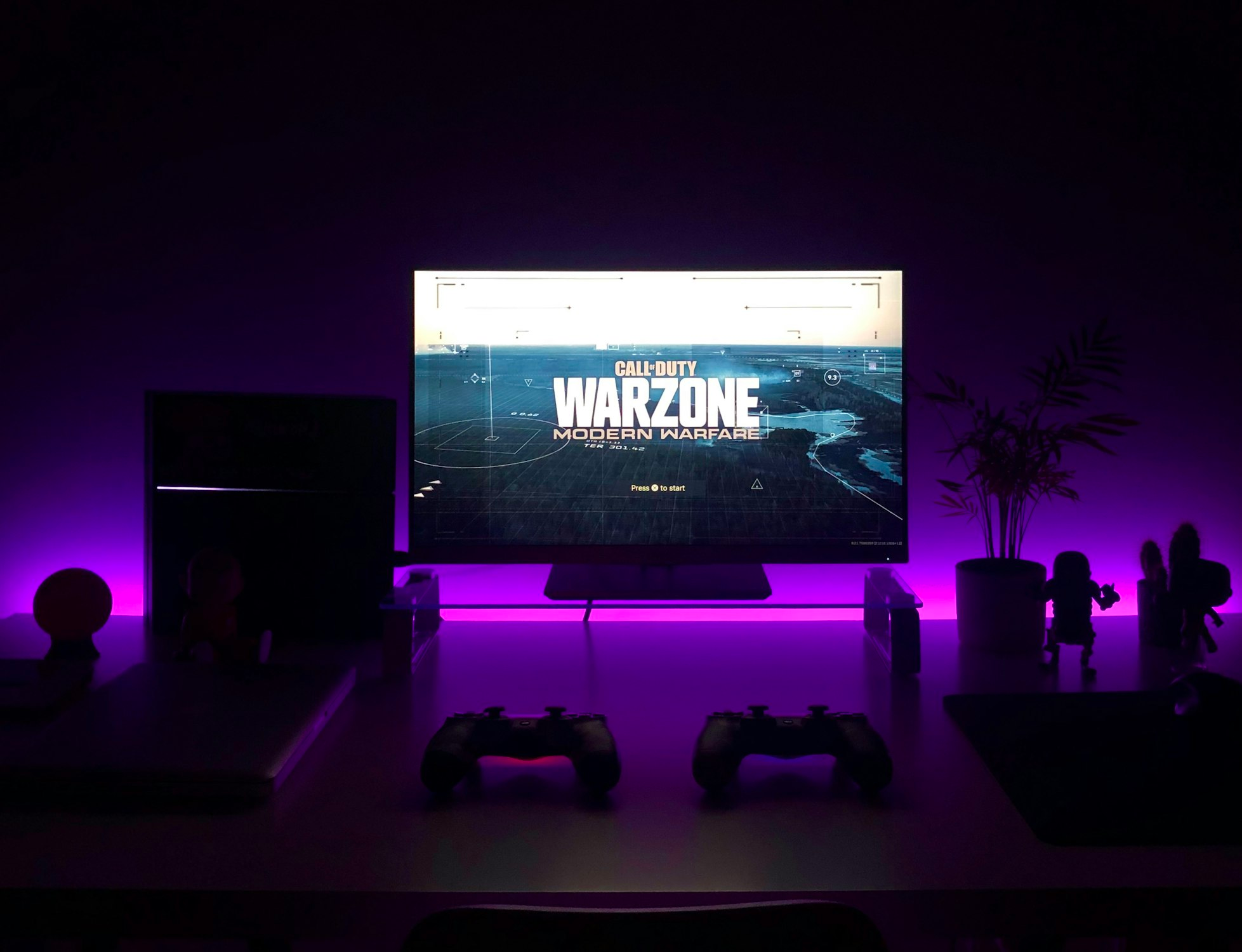 Call of Duty Warzone title screen on a TV with purple ambient lighting.