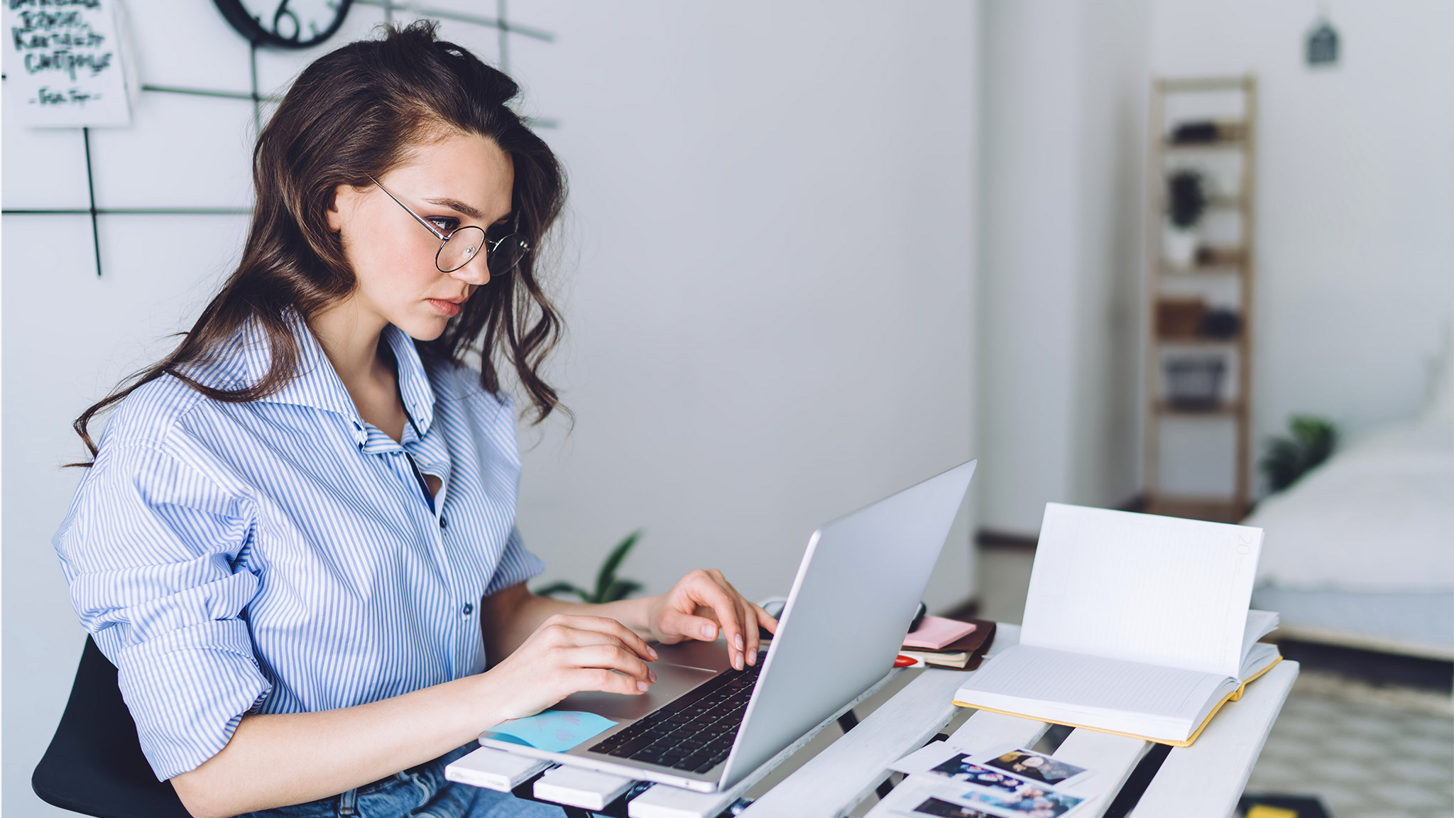 female in glasses in casual clothes typing on laptop