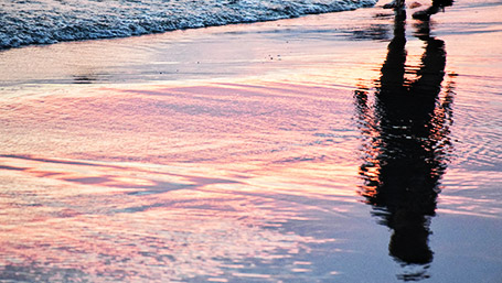 A person walking by the beach reflection