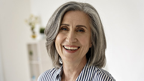 Cheerful satisfied 50s mature woman laughing looking at camera at home.