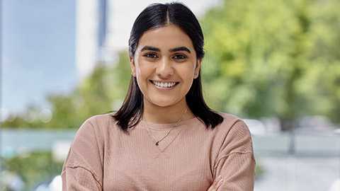 Smile, portrait and face of a young woman at home with arms crossed, happiness and confidence.