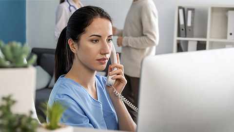 Female receptionist talking by phone in clinic