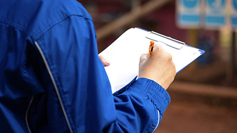 A safety supervisor or manager is writing down on paper for taking note during safety audit