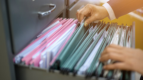 man managing pile of documents in a drawer