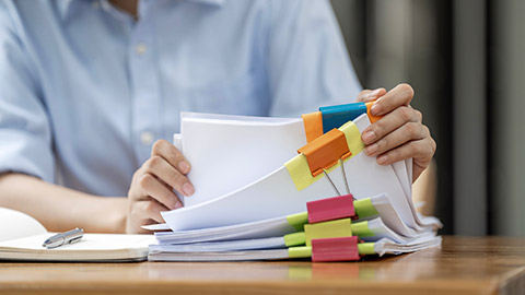 woman hands working in Stacks of paper files for searching and checking unfinished document