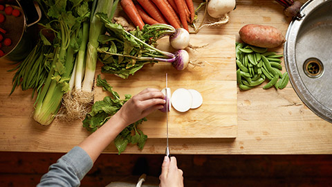 Cutting, board and hands with vegetables for healthy food, cooking or preperation of soup ingredients on table