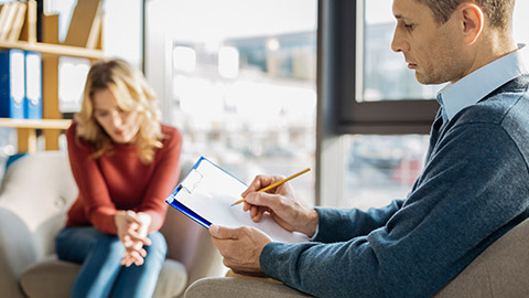 Serious professional male therapist holding his notes and writing in them while putting a diagnosis