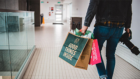 A person walking, carrying shopping bags from a series of different retail outlets