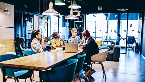 A small team of marketers seated in a meeting room, discussing their organisation's upcoming promotions and strategy