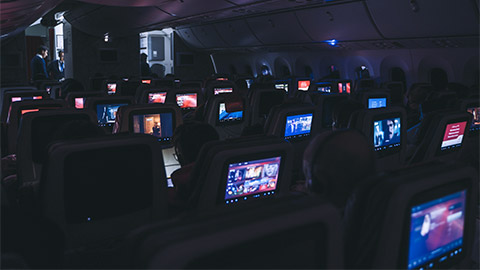 A number of passengers consuming digital media using their personal screens, on a night flight