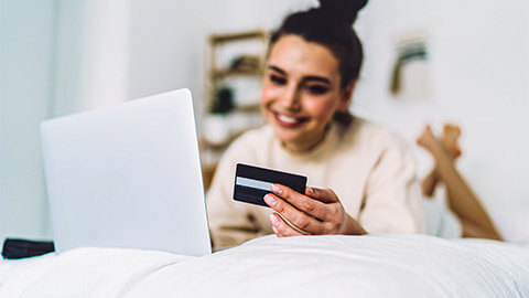 A person spending they day at home, making an online purchase from the comfort of their own bed