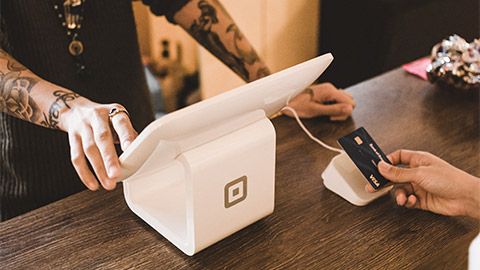 A customer making a purchase using a contactless payment system at a retailer's counter