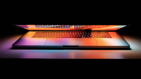 A close up of a MacBook Pro booting up in the dark