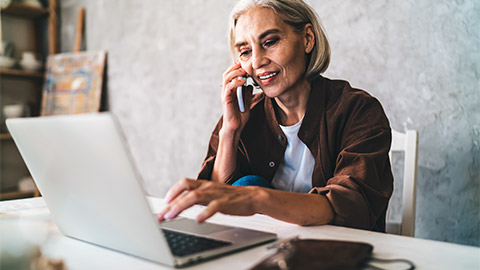 A business owner on the phone with their accountant, being walked through the accountant's new file upload service, before submitting taxes