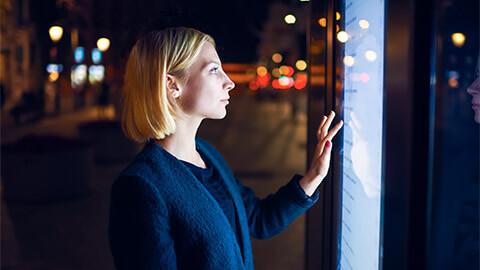 A commuter purchasing a train fare using a self-service touch screen, late in the evening