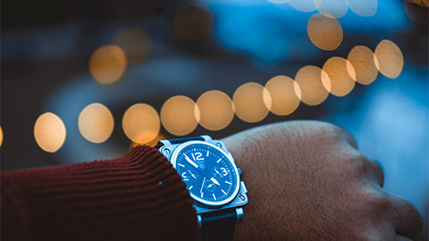 A person looking down at their wrist watch, checking the time