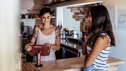 A person having a pleasant conversation with the a staff member when ordering a coffee