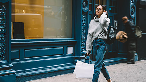 A person walking down the street miling and happy after shopping