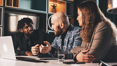 A business leader in serious discussion with 2 colleagues