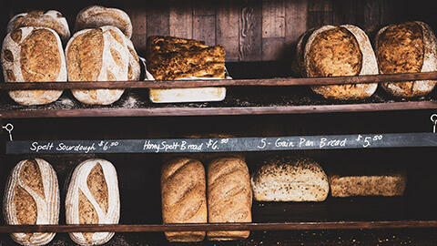 A rack of bread in a bakery with handwritten price tags