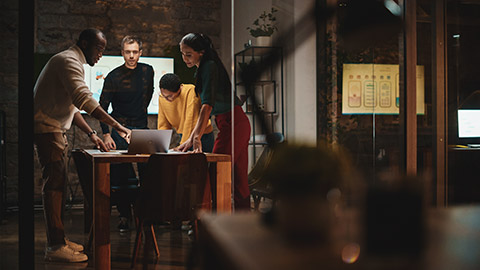 A diverse marketing team discussing a project in a meeting room at night