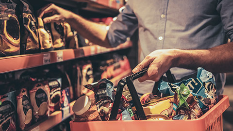 A close view of a shopper carrying a basket of food