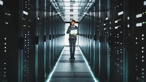 An IT professional walking down the hall of a large server room