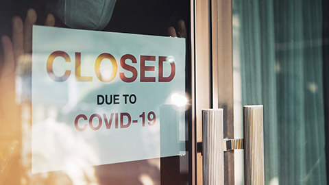 A sign in the window of a business shut due to COVID