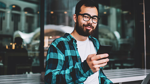 A smiling, confident young hipster at a cafe working on a freelance project