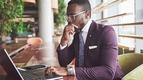 A well-dressed professional absorbing emails on their laptop at the beginning of their workday