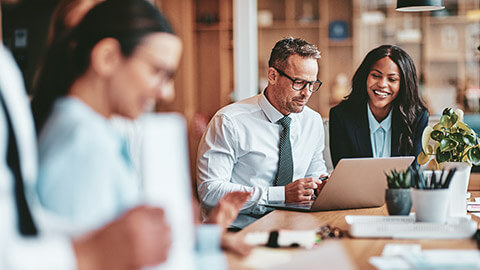 2 financial advisors discussing business in a busy office space