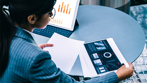 A professional seated at a table, reviewing the projected returns of an aquisition their ogranisation intends to make