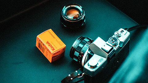 A film camera and a roll of brand new Kodak film still in its box