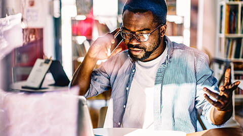 A business owner receiving difficult news over the phone, regarding their business