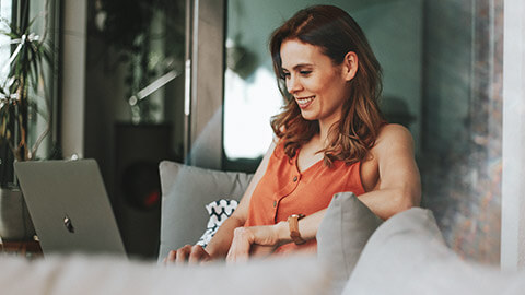 A marketing executive sitting in a relaxed environment looking at information on a laptop