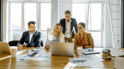 Group of a young office employees dressed casually in the suits having some office work at the large meeting table