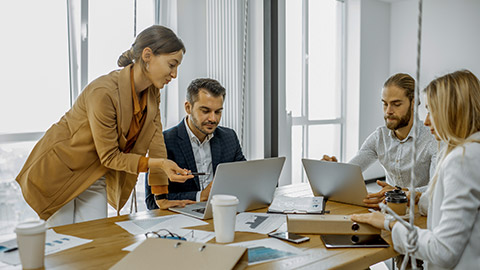 Group of a young office employees dressed casually in the suits having some office work at the meeting table in the bright office