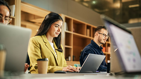 focus to a young woman working and collaborating with colleagues