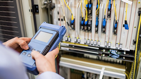 Technician using digital cable analyzer in server room